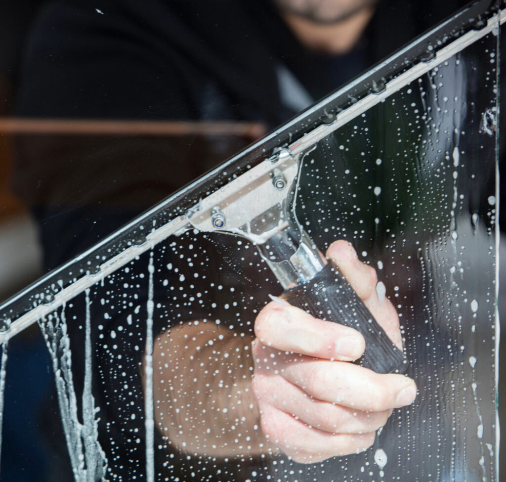 Fönsterputsare rengör glasräcke med professionell utrustning.